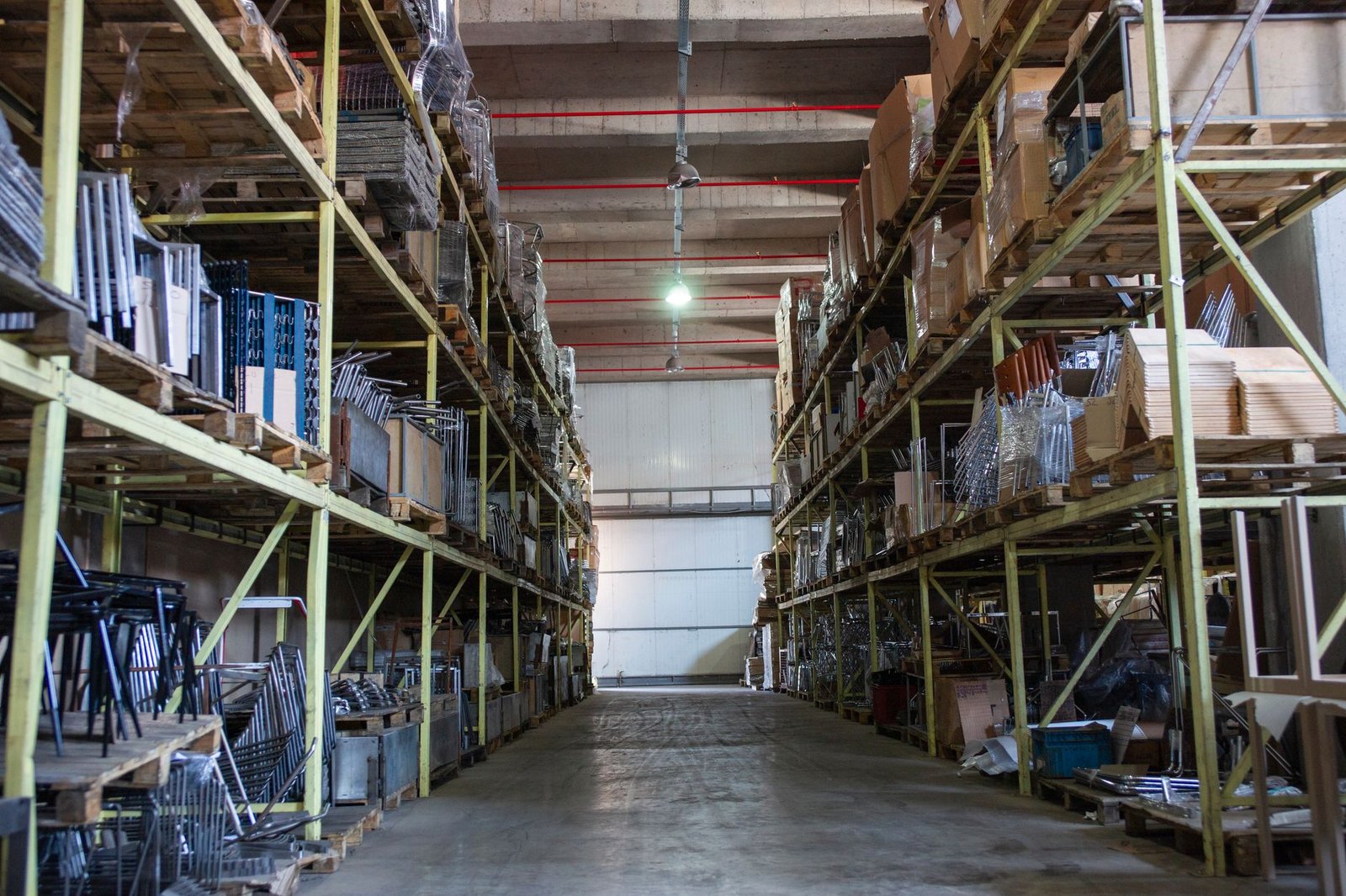 Pasillo de almacén industrial con racks cargados de tarimas hasta la altura de cubierta