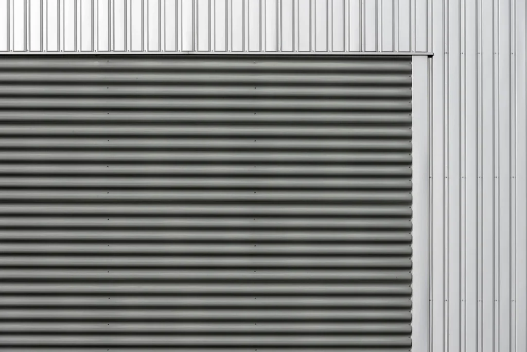Muro de nave industrial con lámina acanalada horizontal y panel metálico vertical