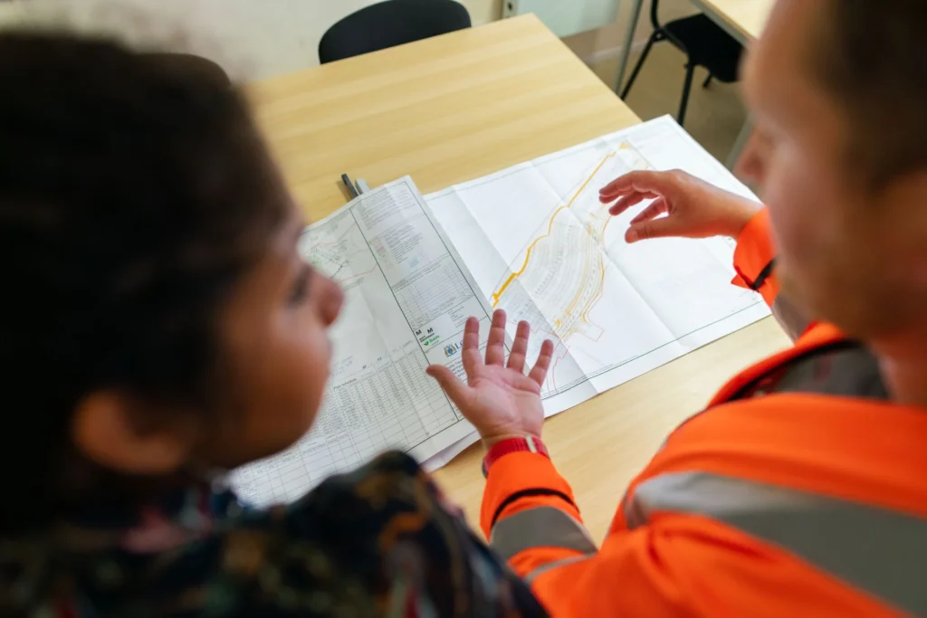 Dos personas revisando planos y documentos de obra sobre una mesa