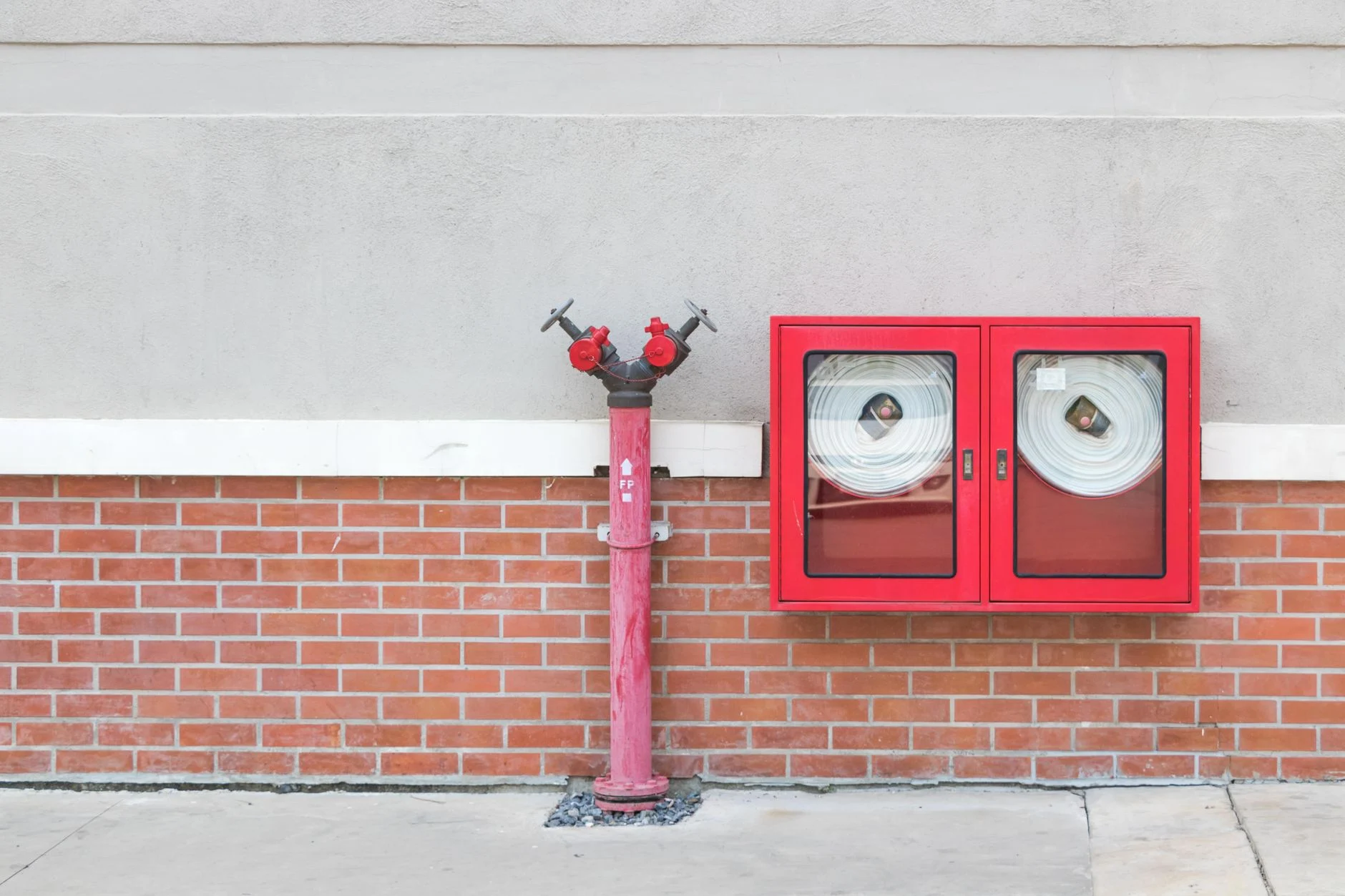 Hidrante de edificio junto a un gabinete rojo con dos mangueras contra incendio