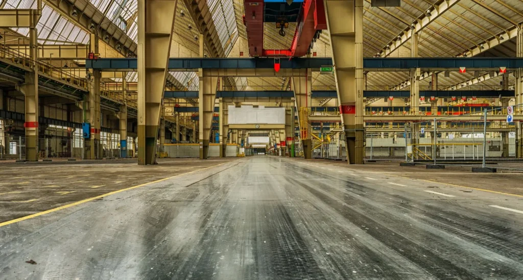 Interior de una nave de manufactura con grúas viajeras, columnas de acero y piso de concreto